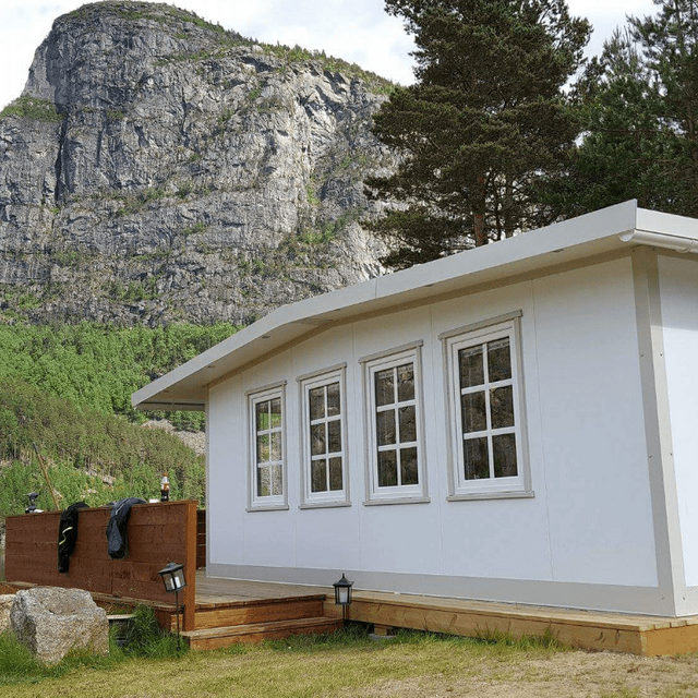 Spikertelt ved innsjø med fjell i bakgrunnen